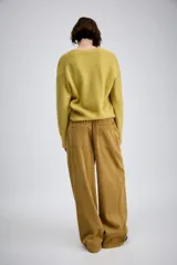 Pantalón de tiro medio confeccionado en tejido de pana, con diseño de pierna ancha, bolsillos delanteros y traseros, y cierre frontal con cremallera y botón.