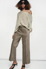 Pantalón de corte cropped flare confeccionado en tejido con lana. Presenta tiro medio, cintura con trabillas, bolsillos laterales ocultos y detalle de nervio frontal. Cierre con cremallera, botón y ganchos metálicos.