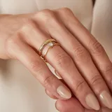 Anillo solitario de oro amarillo 18k con piedra central de circonia engarzada en cuatro puntas, acompañado por una alianza lisa de oro a juego.