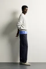 Pantalón negro confeccionado en mezcla de algodón, con cintura elástica, bolsillos frontales y cierre con cremallera y botón.