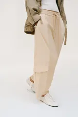 Pantalón de tiro medio con cintura elástica ajustable con cordón. Presenta un diseño de paneles laterales en tejido técnico contrastante y bolsillos tipo cargo. Su corte es holgado con pernera que se estrecha hacia el tobillo.