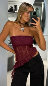 Top strapless de encaje color bordó, con diseño asimétrico y terminación con volados en el ruedo.