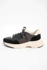 Zapatilla urbana de cuero con diseño de paneles en tonos negro, marrón oscuro y beige. Presenta una suela de plataforma robusta en color beige y cordones jaspeados.