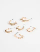 Set de tres pares de aros dorados, tipo argolla, con diferentes diseños texturizados y acabados irregulares.