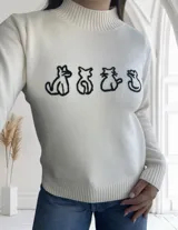 Sweater color crudo de punto con cuello alto y estampado frontal de siluetas de gatos en negro.