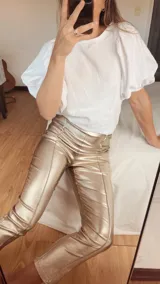 Pantalón dorado de gabardina engomada, corte recto con alforza central y cortes.