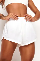 Short deportivo de color blanco con cintura elástica fruncida, aberturas laterales en el dobladillo y forro interno anatómico.