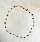 Collar delicado de cadena dorada con pequeñas piedras naturales en tonos variados, dispuestas de forma sutil a lo largo de la pieza.