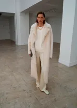 Pantalón de corte recto y tiro medio, confeccionado en tejido satinado con forro interior. Presenta cintura elástica, dos bolsillos laterales y aberturas en los bajos.