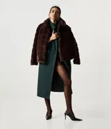 Abrigo largo de paño color verde oscuro, con solapas amplias tipo blazer, cierre frontal cruzado con botones y abertura trasera. Diseño estructurado y elegante.
