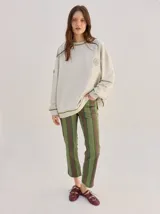 Pantalón de tiro medio con diseño de rayas verticales en tonos marrones, naranjas y amarillos, de corte recto y holgado.