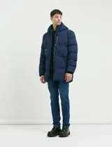 Campera puffer de corte largo, color verde militar, con capucha fija, cierre frontal y puños elásticos internos.