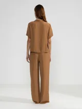 Pantalón palazzo negro de crepe con cintura elastizada, bolsillos laterales y terminaciones en cobre.