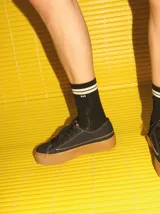 Championes de lona negra con plataforma y puntera de goma marrón, cordones negros y costuras en contraste.