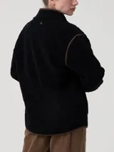 Chaqueta polar acolchada color azul marino, con diseño de rombos y ribetes en contraste color marrón. Presenta cuello alto, cierre frontal con botones y bolsillos frontales estructurados.