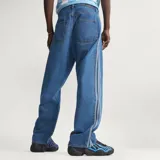 Pantalón de denim azul de corte holgado, tiro medio y diseño clásico con las tres tiras características de Adidas a lo largo de los laterales.