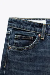 Jeans de mezclilla azul oscuro con efecto lavado, tiro bajo y pierna ancha extra larga. Modelo de cinco bolsillos con cierre frontal de cremallera y botón metálico.