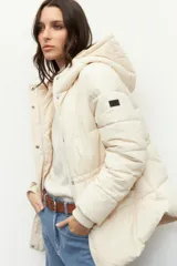 Campera puffer larga color beige, con diseño acolchado horizontal, capucha y bolsillos laterales. Cuenta con cierre frontal con cremallera y solapa con broches a presión, además de puños elastizados y aplique con logo en la manga.