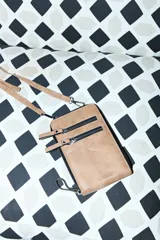 Porta celular de cuero sintético color marrón, con diseño rectangular, cierre principal y dos bolsillos frontales con cierre. Incluye correa larga regulable y extraíble, y cuenta con el logo de la marca grabado en la parte inferior.