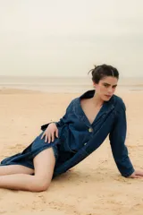 Tapado largo de jean con dos amplios tajos laterales que le dan movimiento y estilo. Cuenta con dos grandes bolsillos delanteros y un botón de guampa, distintivo de la marca.