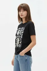 Remera de manga corta de algodón en color blanco, con cuello redondo y diseño holgado. Cuenta con un estampado frontal central con detalles metalizados estilo foil.