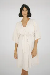 Bata maternal de algodón con diseño envolvente, escote en V y lazo ajustable en la cintura. Presenta mangas cortas amplias y un corte holgado que se adapta a la silueta.