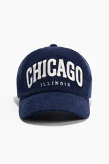 Gorra de pana azul marino de algodón, con bordado frontal en color blanco y cierre ajustable con hebilla metálica en la parte posterior.