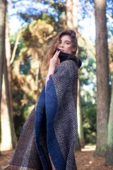 Poncho marrón con diseño de espiga en tonos beige y azul. Tiene cuello alto negro y flecos en el ruedo.