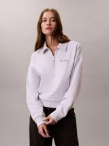 Buzo Calvin Klein de tejido french terry color lila claro, con cuello tipo polo y cierre de media cremallera. Cuenta con el logo de la marca bordado en el pecho y diseño de manga larga.