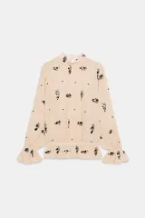 Blusa de cuello subido y manga larga con puños acampanados elásticos. Confeccionada en tejido semitransparente color beige con bordado de lentejuelas oscuras. Presenta cierre en la espalda con abertura y botones ocultos.