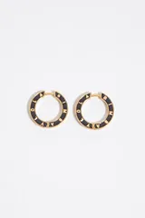 Aros tipo argolla metálicos en tono dorado con esmalte negro y letras grabadas en relieve con el nombre de la marca.
