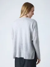 Suéter poncho de mujer, color gris claro, tejido en cashmere, con cuello en V, mangas largas acanaladas y aberturas laterales.