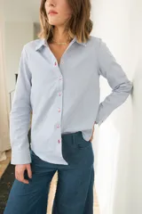 Camisa de corte clásico confeccionada en algodón con estampado de rayas verticales en azul y blanco. Presenta cuello camisero, cierre frontal con botones y mangas largas con puños abotonados.