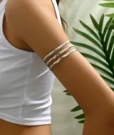 Juego de tres brazaletes abiertos para el brazo, color plateado, con textura martillada o irregular.