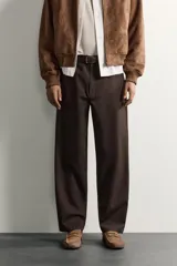 Pantalón chino de corte regular, color marrón oscuro, con cierre frontal de cremallera y botón, bolsillos laterales y bolsillos traseros de vivo.