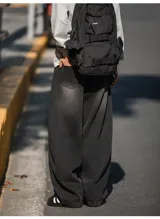 Pantalón de jean negro con lavado oscuro y efecto desgastado, de corte muy ancho (baggy) y tiro medio/alto con cintura elástica. Presenta bolsillos delanteros y traseros.