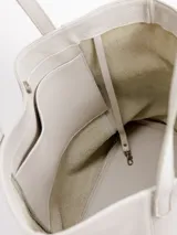 Cartera tote de cuero natural color beige, con doble asa larga para hombro y cierre superior con broche.