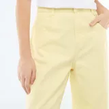 Pantalón de corte globo en color amarillo pastel, con tiro alto, cierre frontal con botón y bolsillos laterales.