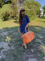 Bolso de lona fucsia combinado con detalles y asas de cuero tostado, de diseño espacioso con cierre superior y correa ajustable.