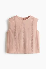 Blusa sin mangas de color rosado, confeccionada en tejido con efecto arrugado y detalles de inserciones de encaje vertical en el frente. Presenta escote redondo, cierre posterior con botón y abertura de cerradura, y corte recto.