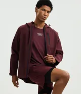Campera deportiva Get Over de hombre, color bordó, con capucha ajustable, cierre frontal y bolsillos con cremallera. Confeccionada en tejido técnico resistente al agua.