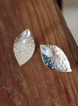 Par de aros plateados con forma de hoja y detalle de cristal facetado.