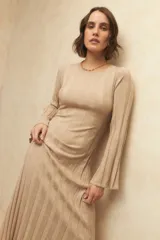 Vestido midi de punto acanalado en color gris, con mangas largas acampanadas y aberturas laterales en el ruedo. Presenta un diseño ajustado al cuerpo.