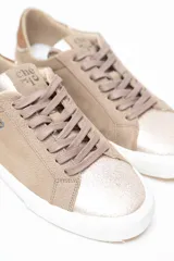 Championes de cuero legítimo color dorado con acabado metalizado, pasamontañas con cordones al tono y suela blanca con detalles de perforaciones laterales y talón contrastante.