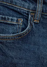 Jeans mom fit de tiro alto y lavado azul oscuro, con diseño clásico de cinco bolsillos, trabillas para cinturón y cierre frontal con cremallera y botón.