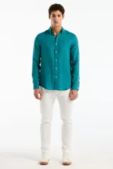 Camisa de lino de manga larga color verde turquesa, con cuello camisero, cierre frontal de botones y un bolsillo ojal en el pecho.