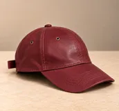 Gorro tipo visera de cuero color marrón, con ojales metálicos de ventilación y costuras pespunteadas en la visera.