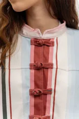 Chaqueta liviana de jean celeste con cuello mao, cierre frontal con alamares y detalle de bordados florales.