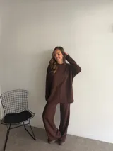 Conjunto de dos piezas compuesto por un sweater de cuello redondo y manga larga, y un pantalón de corte recto y tiro alto. Ambas prendas presentan una textura tejida con diseño de trenzas verticales.