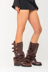 Botas de cuero marrón con caña alta y tres correas con hebillas doradas.